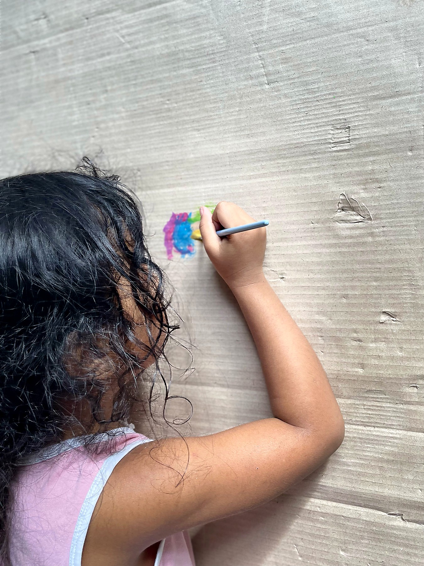 A child painting a rainbow on cardboard